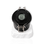 Black lash glue storage container with digital humidity display on the lid displayed on a white stone surface.