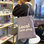 Local Lash Plug tote bag displayed inside a lash studio, showing a practical accessory for lash artists and beauty professionals