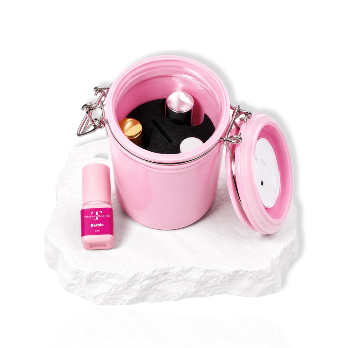 Open pink lash glue storage container showing lash adhesive bottles and accessories inside.