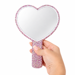 Pink heart-shaped crystal lash mirror with rhinestone-covered handle held by a hand, decorative eyelash extension mirror for lash artists and beauty professionals