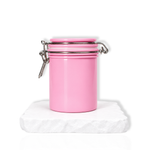 Pink lash glue storage container with airtight lid displayed on a white stone surface.