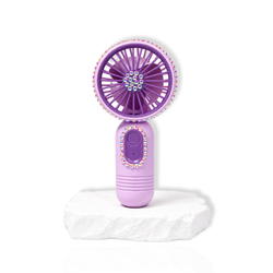 Purple portable lash fan with rhinestone detailing displayed on a white stone surface.