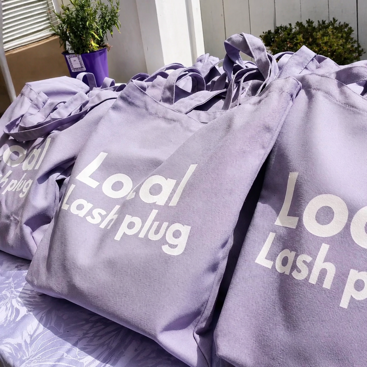 Purple swag bags prepared for attendees at a lash artist wellness event.