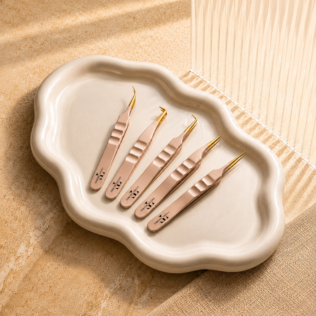 Set of rose gold lash tweezers arranged on a white tray for eyelash extension applications.