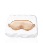 Silk lash mask with padded eye-shaped design and adjustable strap displayed on a white stone surface.