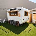 Small outdoor coffee trailer setup with seating area and event decorations.