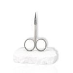 Stainless steel precision lash scissors displayed upright on a white stone surface against a white background.