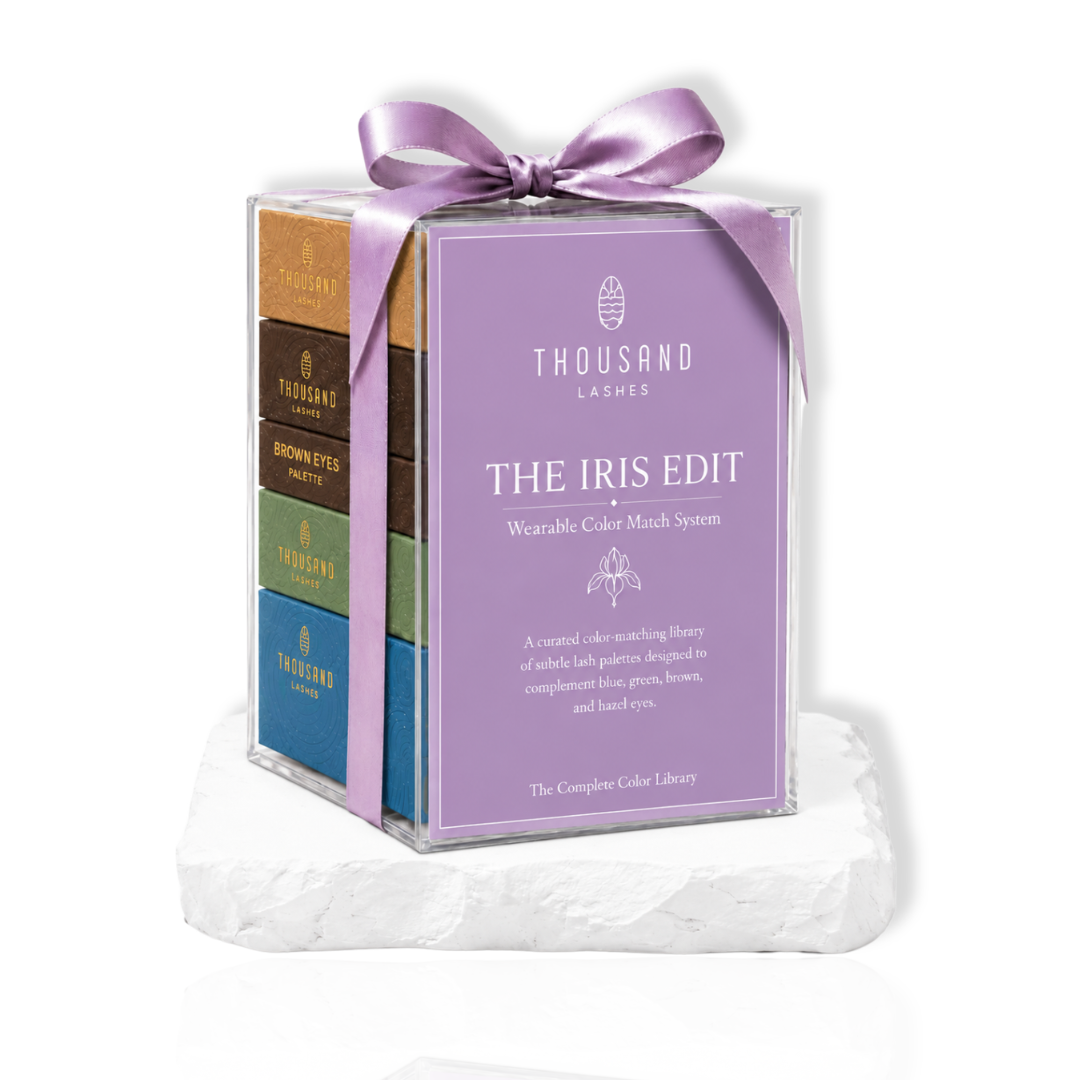 The Iris Edit wearable color lash collection by ThousandLashes displayed in a purple gift box with a ribbon on a white stone base.