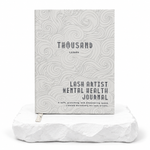 Thousandlashes Lash Artist Mental Health Journal with a gray wave-pattern cover displayed on a white stone surface.
