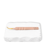 Thousandlashes nude curved lash tweezer shown from the reverse side on a white stone surface.