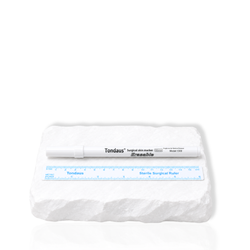 White lash mapping pen with a sterile surgical ruler displayed on a white stone surface.