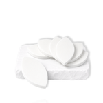 White leaf-shaped makeup sponges stacked and arranged on a white stone slab.