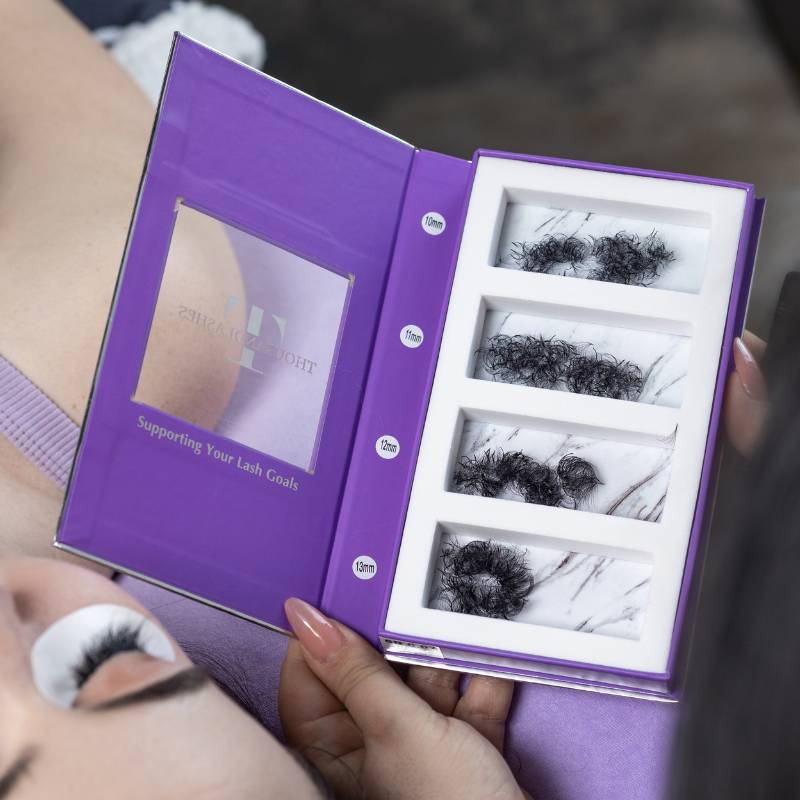 Lash artist holding an open ThousandLashes Pro Made Volume Fans Mix Length tray while applying volume eyelash extensions to a client