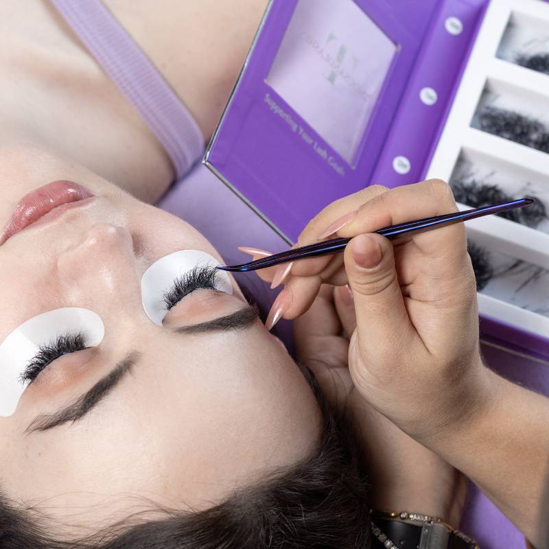 Lash artist using a Thousandlashes Noir Collection curved tweezer during an eyelash extension application.