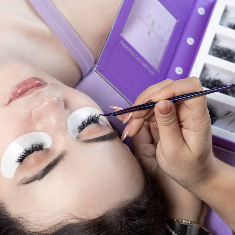 Professional lash artist using tweezers to apply ThousandLashes Pro Made Volume Fans during a volume lash extension appointment