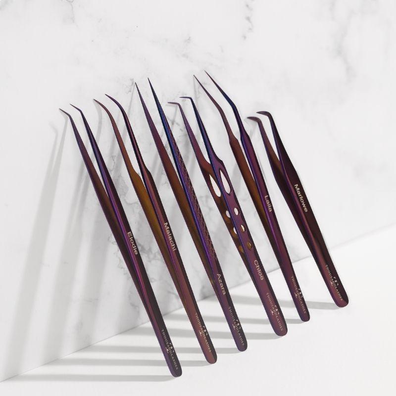 Set of purple professional eyelash extension tweezers arranged on a white marble surface for lash application and precision beauty tools.