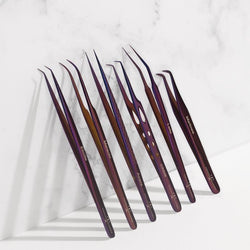 Set of purple professional eyelash extension tweezers arranged on a white marble surface for lash application and precision beauty tools.